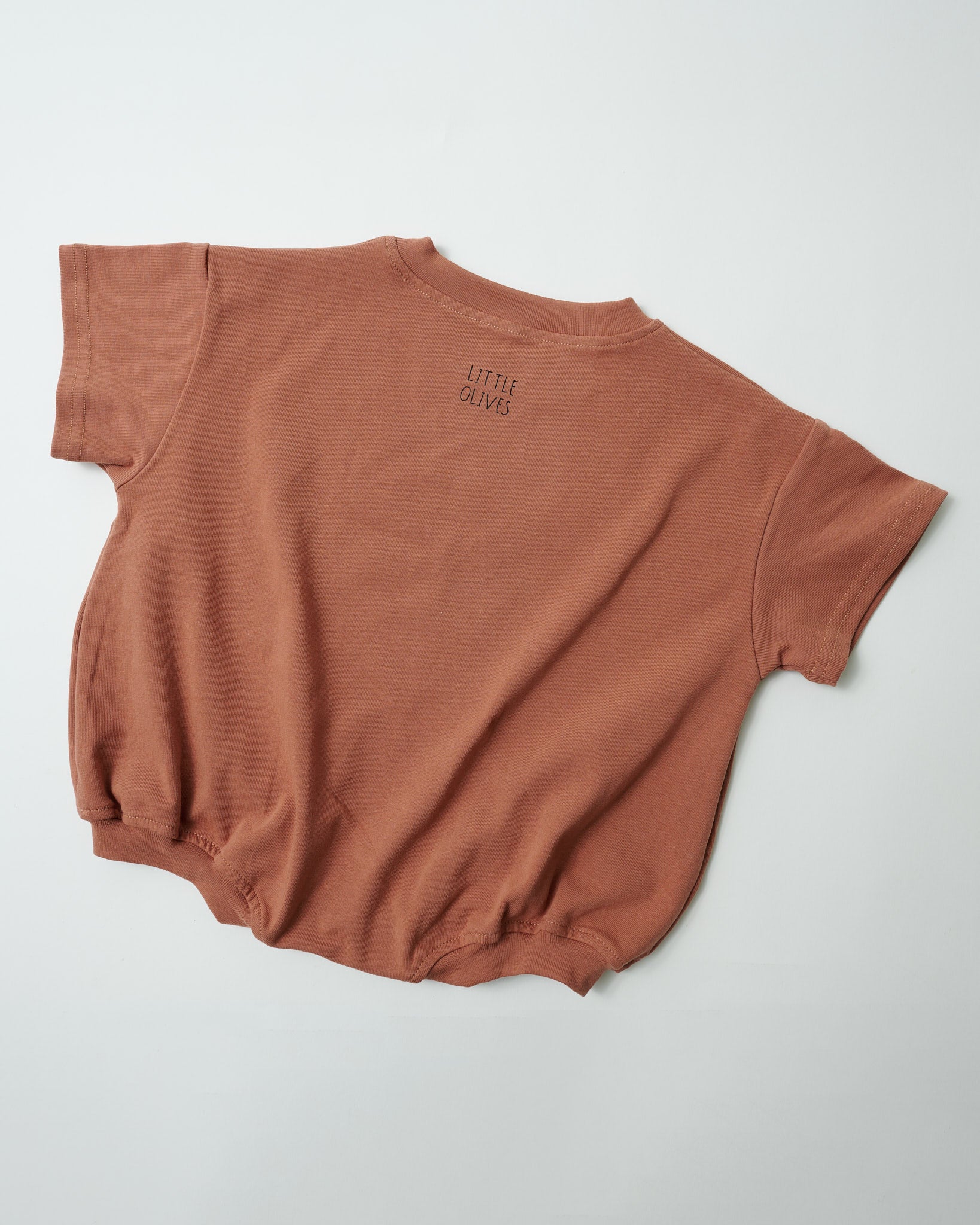 Back view of relaxed fit oversized toddler romper in clay showing high-quality fabric finish with Little Olives logo.