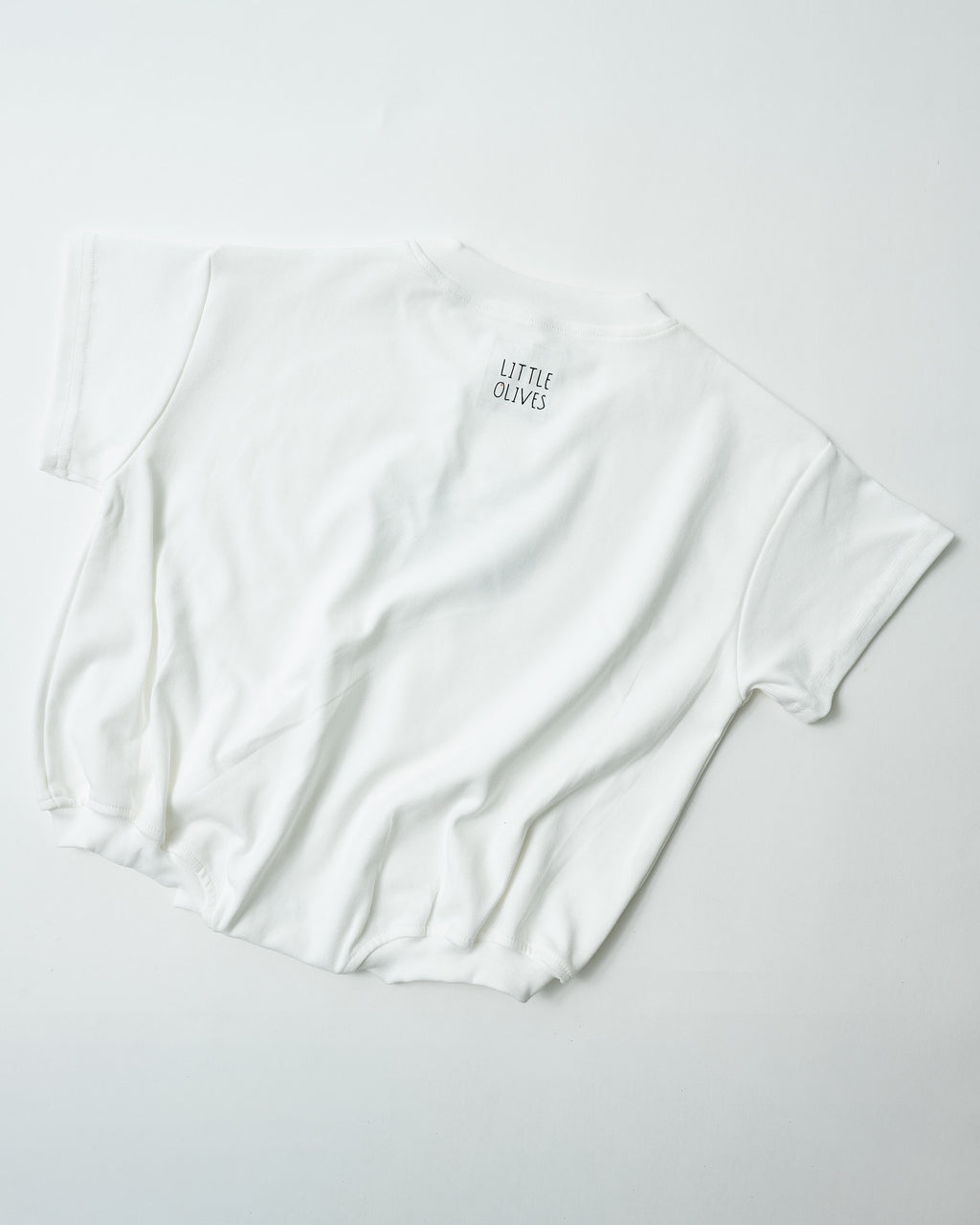 Back view of oversized snow white toddler romper showing the premium relaxed fit with Little Olives logo.