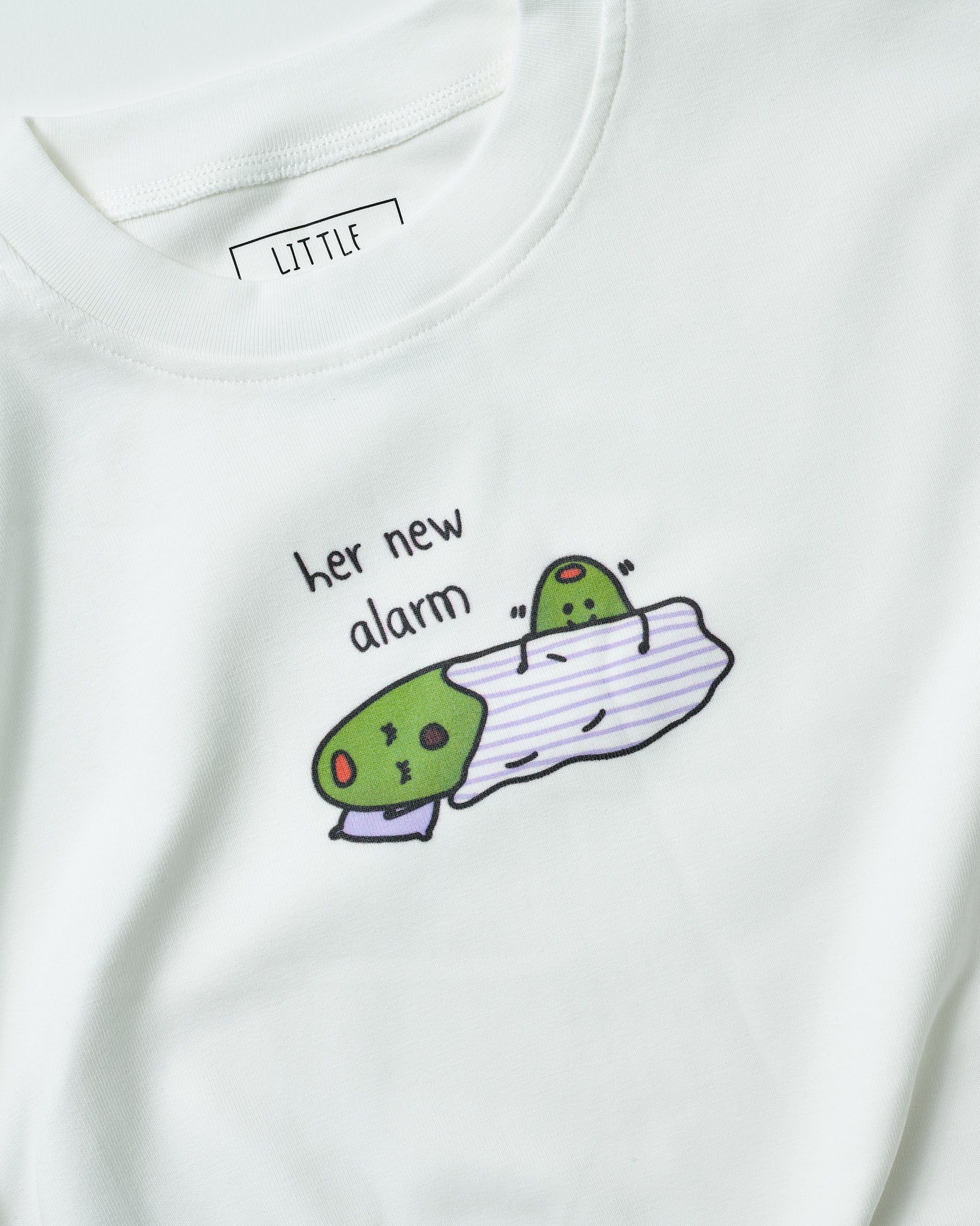 Detailed shot of the minimalist typography "Her New Alarm" digital print on cream fabric with baby character waking the mother