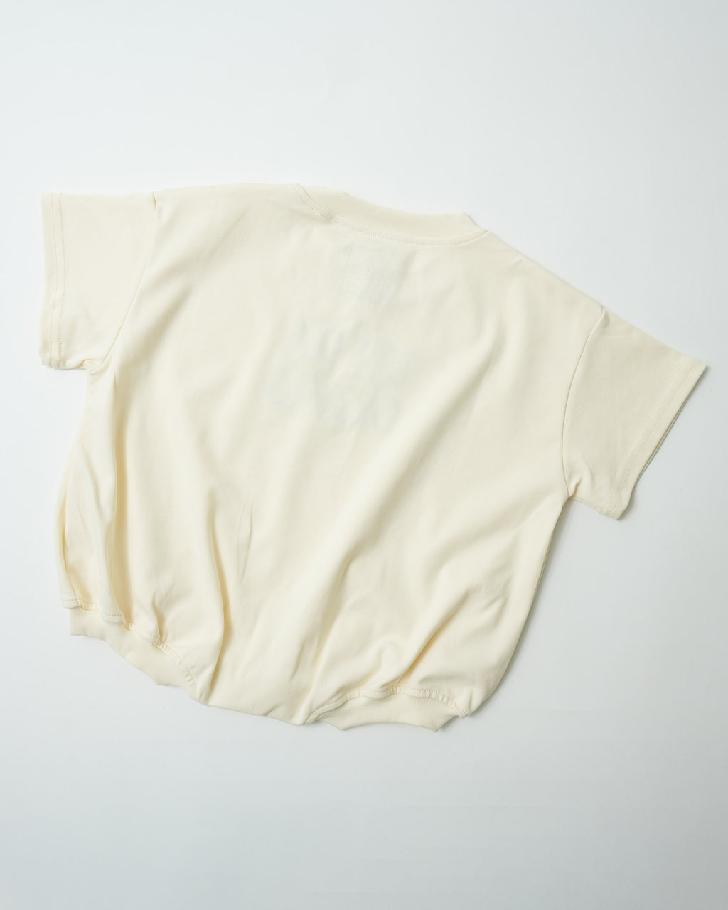 Back view of oversized organic cotton toddler romper in natural cream showing relaxed fit.