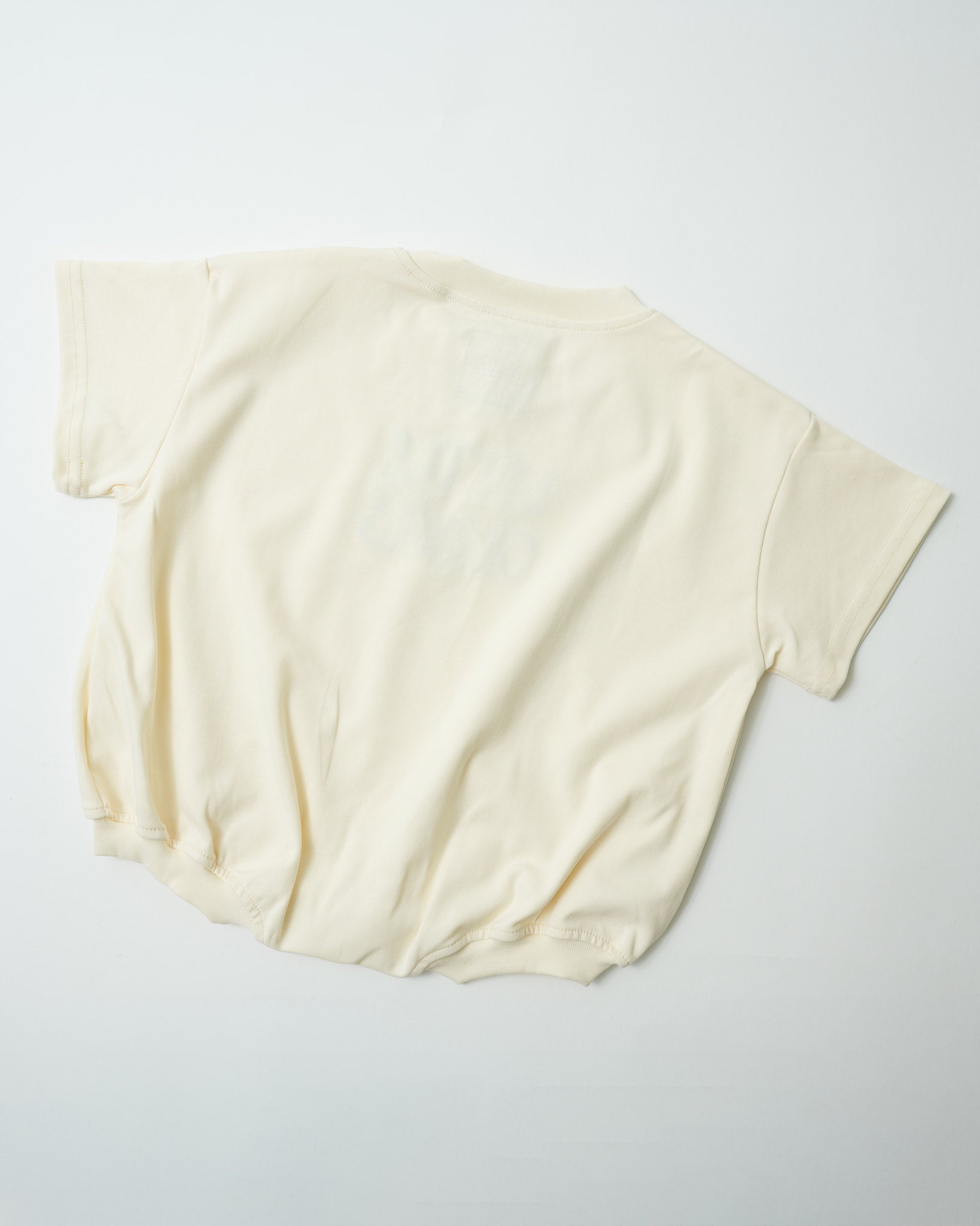 Back view of oversized organic cotton toddler romper in natural cream showing relaxed fit.