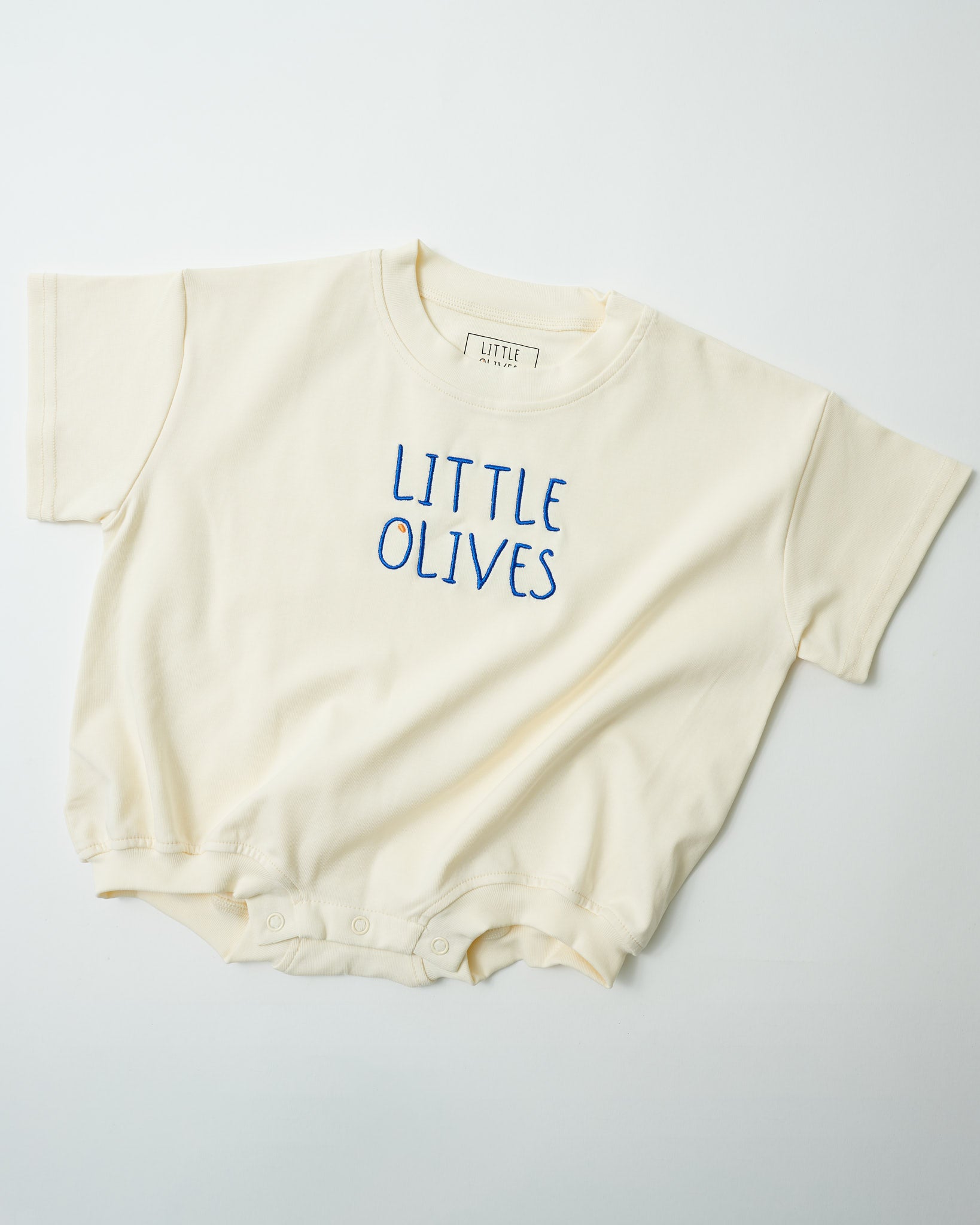 Front view of Little Olives signature embroidered baby romper in natural cream organic cotton.