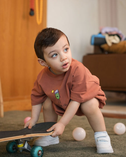 Funny lifestyle shot of a baby awake at dawn skateboarding wearing the clay 5:00am Club romper.